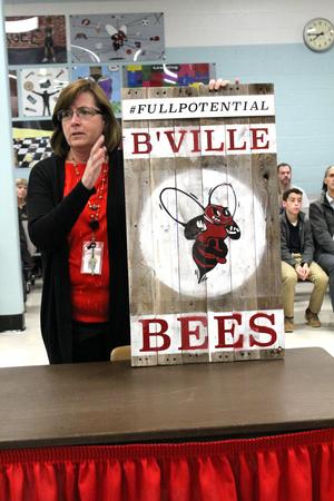 a  woman holds up a sign with a red bee on it