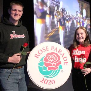 a male and a female hold roses and also hold a sign that says Rose Parade 2020