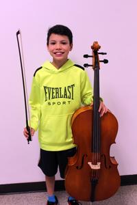 A boy holding a cello is smiling