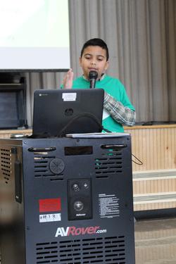 a boy gives a presentation at a computer