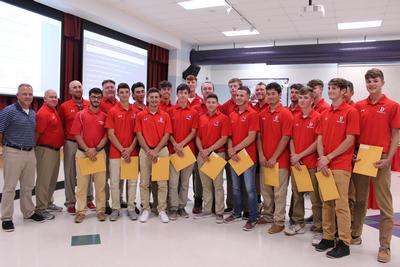 members of the boys baseball team wearing red shirts and holding certificates