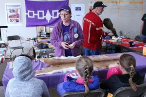 a woman and man show students native american artifacts