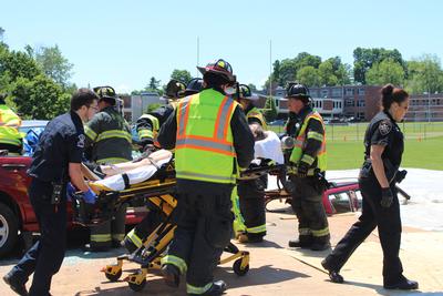 paramedics wheel student away on a stretcher